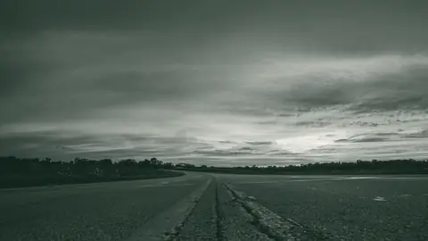 A two-lane highway at dusk, seen from the center line
