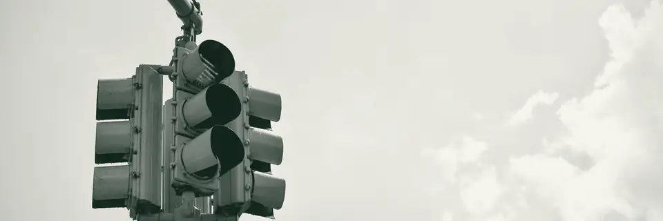 A traffic signal showing red against a pale sky